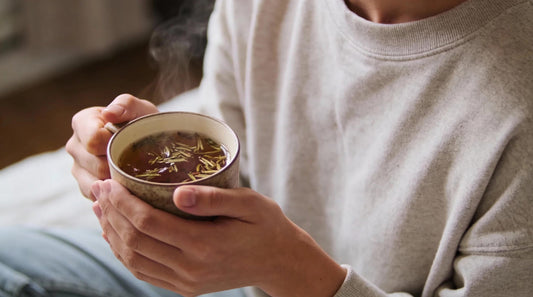 person holding a warm herbal tea supporting internal balance and daily comfort